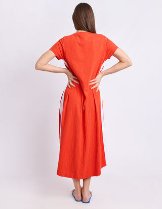 Back view of a woman wearing a bright orange linen maxi dress with white side stripes.