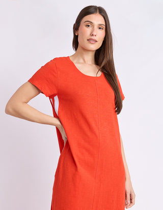Woman wearing a bright orange short sleeve linen-blend summer dress.