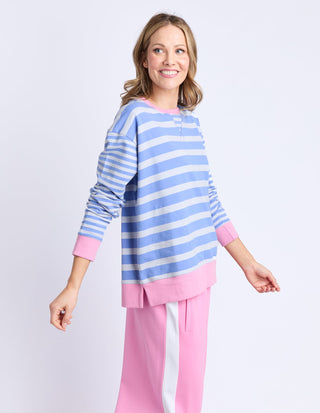 Woman wearing a blue and white striped sweatshirt with pink trim and matching pink pants.