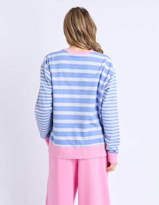 Back view of a woman wearing a blue and white striped sweatshirt and pink lounge pants.