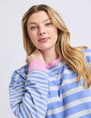 Woman wearing a blue and white striped sweatshirt with pink ribbed cuffs.