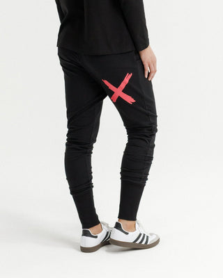 Woman wearing black joggers with a red cross graphic and white sneakers