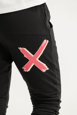 Black joggers with a large pink brushstroke X graphic on the thigh.