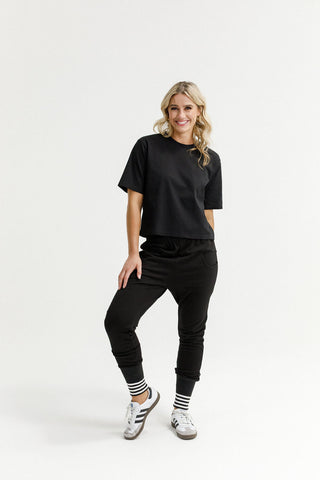 Woman smiling in a black oversized t-shirt and matching black joggers with striped socks.