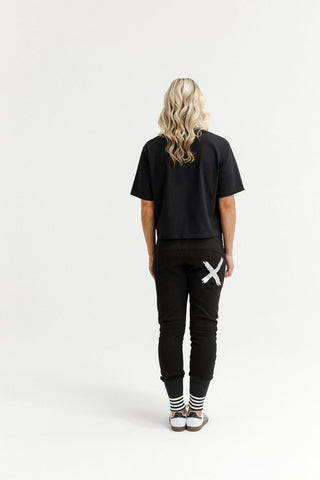 Woman in black t-shirt and joggers with white X graphic on the back.