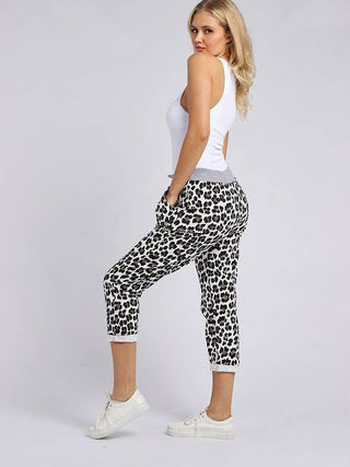 Woman wearing white tank top and leopard print cropped joggers with white sneakers