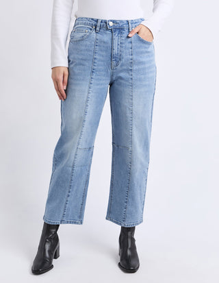 Woman wearing light blue high-waisted straight leg jeans and black ankle boots.