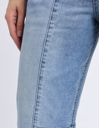 Close-up of a woman wearing light blue denim jeans.
