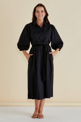 Woman wearing a black long-sleeve midi shirt dress with a belted waist.