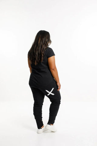 Woman wearing a black short sleeve t-shirt and matching black joggers with a white X detail.