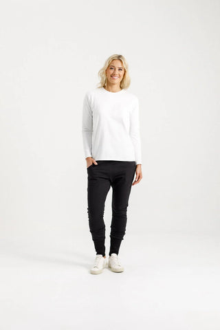 Woman wearing a white long sleeve top and black leisure pants with white sneakers