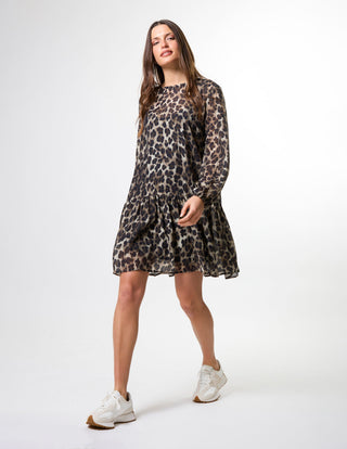 Woman wearing a long-sleeve leopard print mini dress and white sneakers.