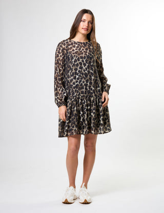Woman wearing a leopard print long-sleeve mini dress and white sneakers.