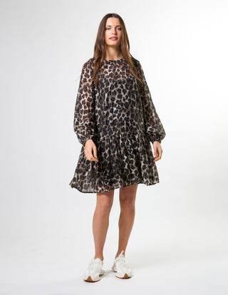 Woman wearing a leopard print long sleeve mini dress and white sneakers.