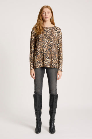 Woman wearing a leopard print long sleeve top, grey skinny jeans, and black knee-high boots.