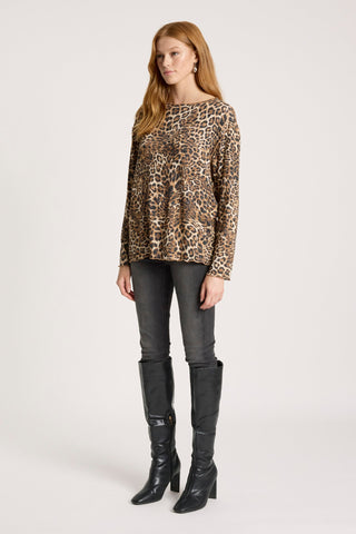 Woman wearing a leopard print long sleeve top, grey skinny jeans, and black knee-high boots.