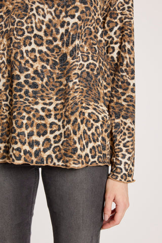 Close-up of a woman wearing a leopard print sweater and dark grey jeans.
