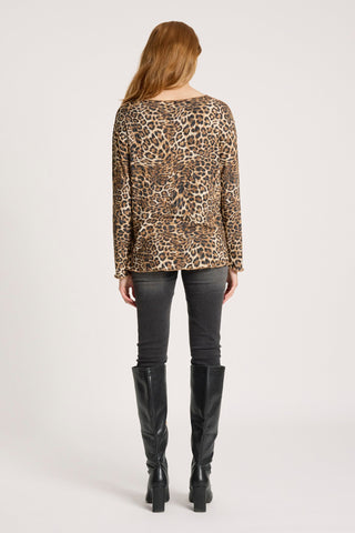 Rear view of a woman wearing a leopard print top, dark grey skinny jeans, and black knee-high boots.