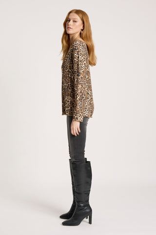 Woman wearing a leopard print blouse, grey skinny jeans, and black high-heeled boots.