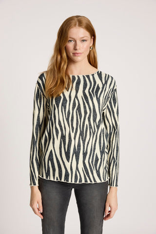 Woman wearing a black and white zebra print long sleeve sweatshirt and dark jeans.