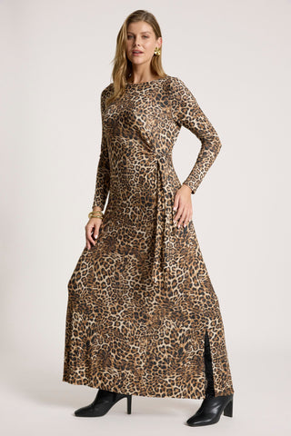 Woman wearing a long-sleeved leopard print maxi dress with a waist tie and side slit.
