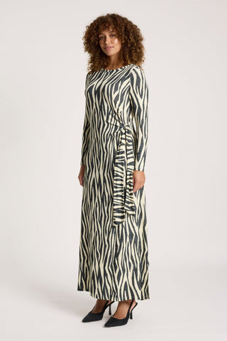 Woman wearing a long-sleeve zebra print maxi dress with a tie waist and black heels.