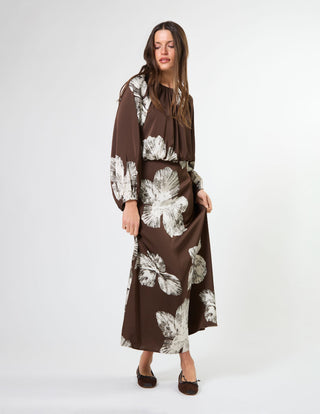 Woman wearing a brown long-sleeve maxi dress with white floral prints and brown pumps.