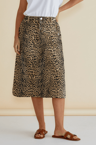 Woman wearing a leopard print midi skirt with tan leather slide sandals.