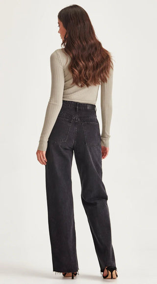Woman wearing a beige ribbed long sleeve top and black wide leg denim jeans.