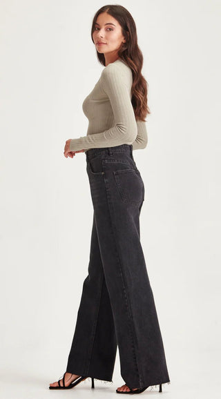 Woman wearing a sage green ribbed long sleeve top and black wide leg denim pants.
