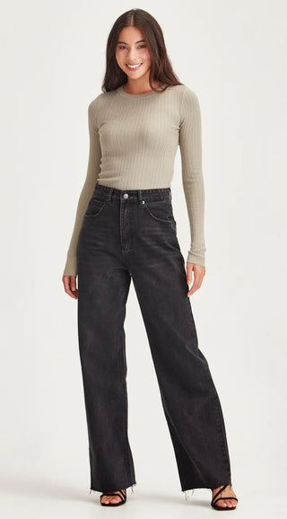 Woman wearing a ribbed sage green long sleeve top and wide leg black denim pants.