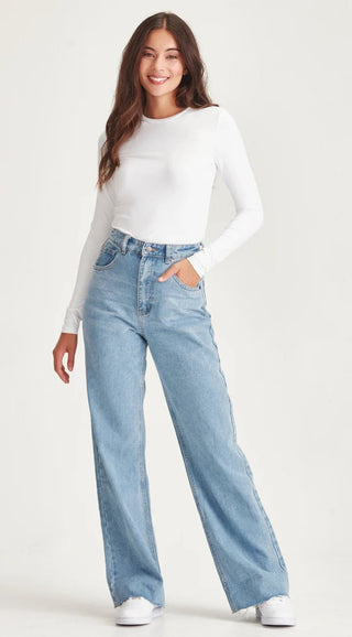 Woman wearing a white long sleeve top and light blue wide leg denim jeans