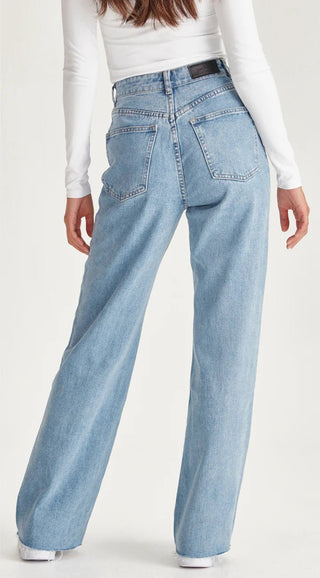 Woman wearing light blue high-waisted wide leg denim jeans from a back view.