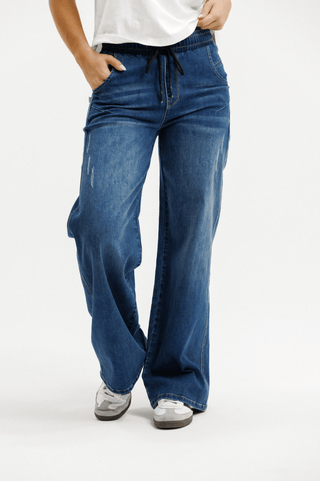 Woman wearing wide-leg blue denim drawstring pants and white sneakers