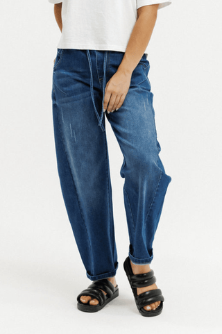 Woman wearing blue wide-leg drawstring denim pants and black platform sandals.