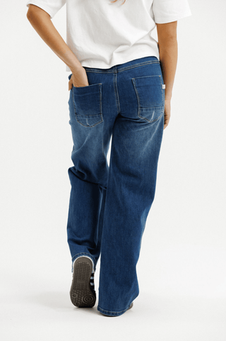 Back view of a person wearing wide-leg blue jeans and a white t-shirt.