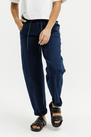 Woman wearing dark blue drawstring waist pants and black chunky sandals.