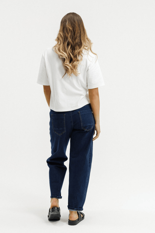 Rear view of a woman wearing a white t-shirt and dark blue wide-leg jeans.