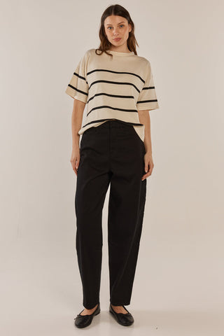 Woman wearing a cream striped t-shirt and black wide-leg trousers with black flats.