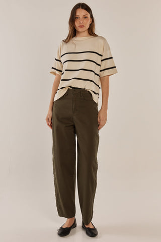 Woman wearing a cream striped t-shirt and olive green wide-leg trousers.