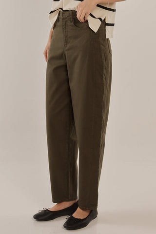 Woman wearing olive green high-waisted wide leg trousers and black ballet flats.