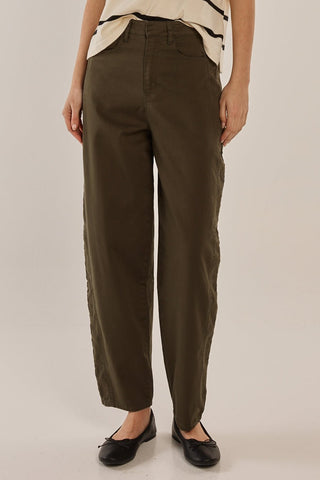 Woman wearing olive green high-waisted wide leg trousers and black ballet flats.