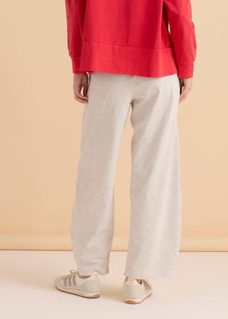 Woman wearing light grey wide-leg lounge pants and white Adidas sneakers.