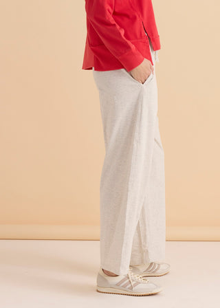Woman wearing light grey wide-leg lounge pants and a red sweatshirt with white sneakers.