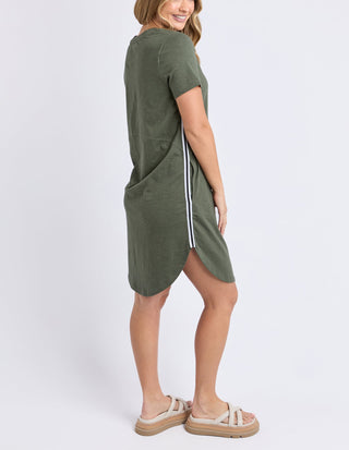 Woman wearing an olive green t-shirt dress with white side stripes and beige sandals.