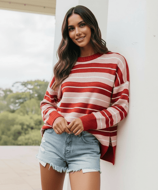 Woman smiling in a red and white striped knit sweatshirt and denim shorts.