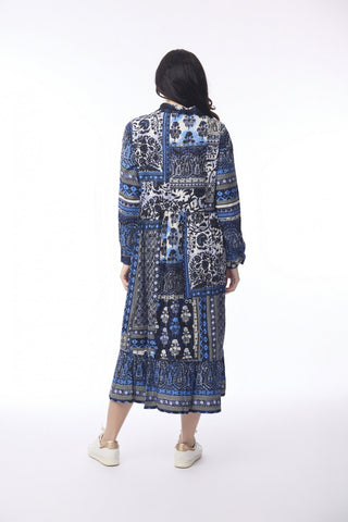 Woman wearing a blue and black patterned maxi dress with long sleeves and a tiered skirt.
