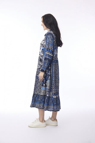 Woman wearing a blue and navy patterned maxi dress with long sleeves and white sneakers.