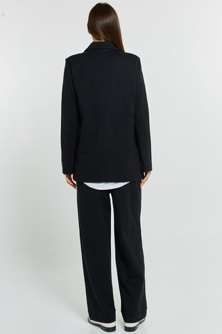 Rear view of a woman wearing a black oversized blazer and matching wide-leg trousers.