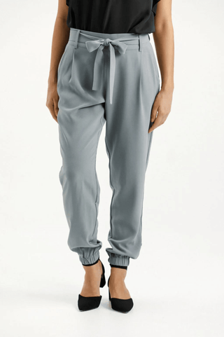 Women's grey high-waisted tie-waist trousers with jogger style cuffs and black heels.